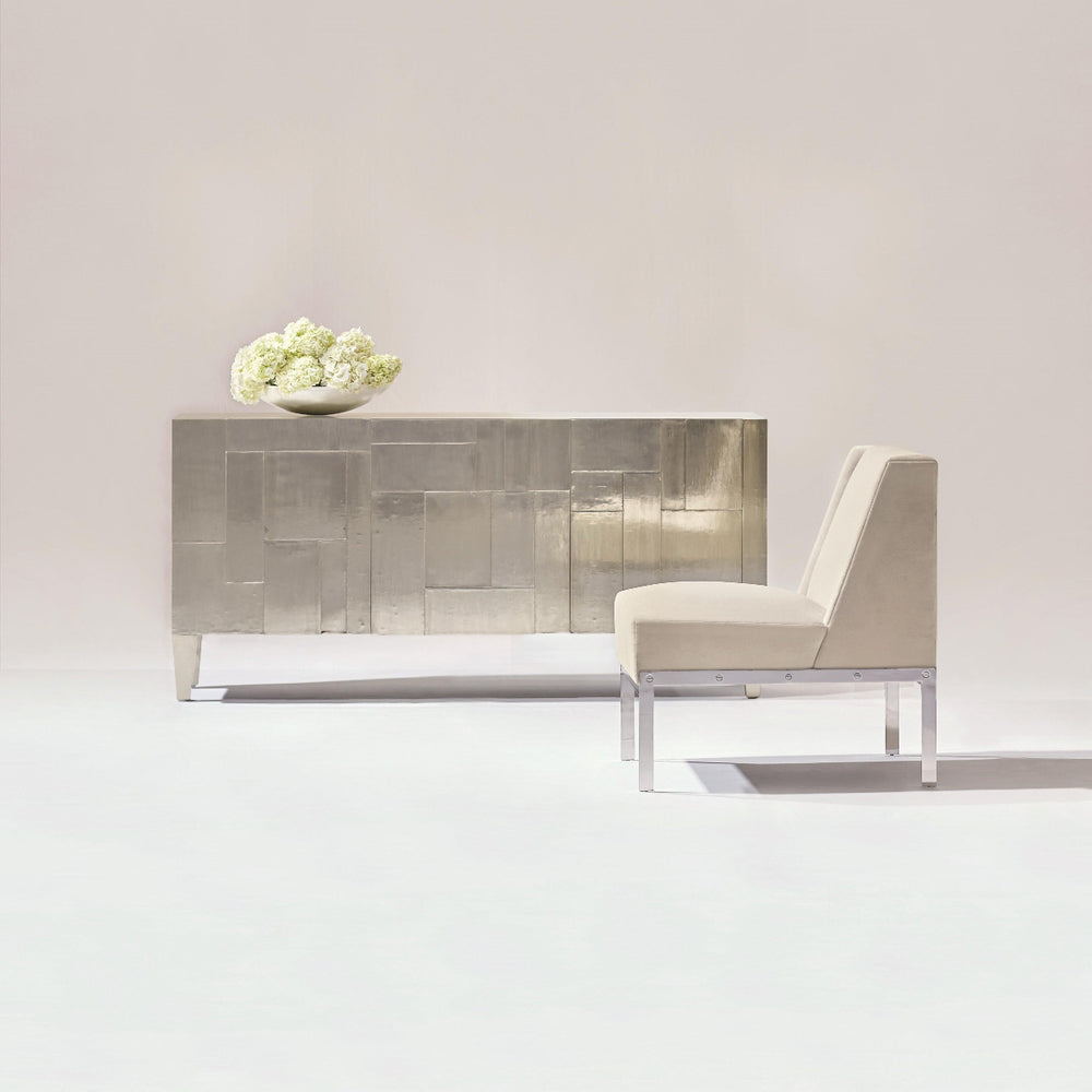 Modern interior with a sleek console table and chair against a plain wall.