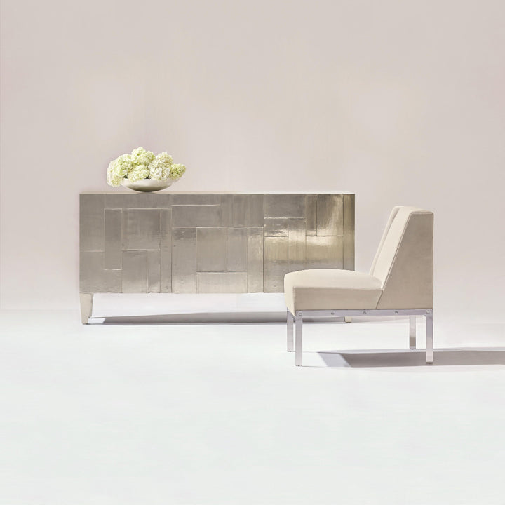 Modern interior with a sleek console table and chair against a plain wall.