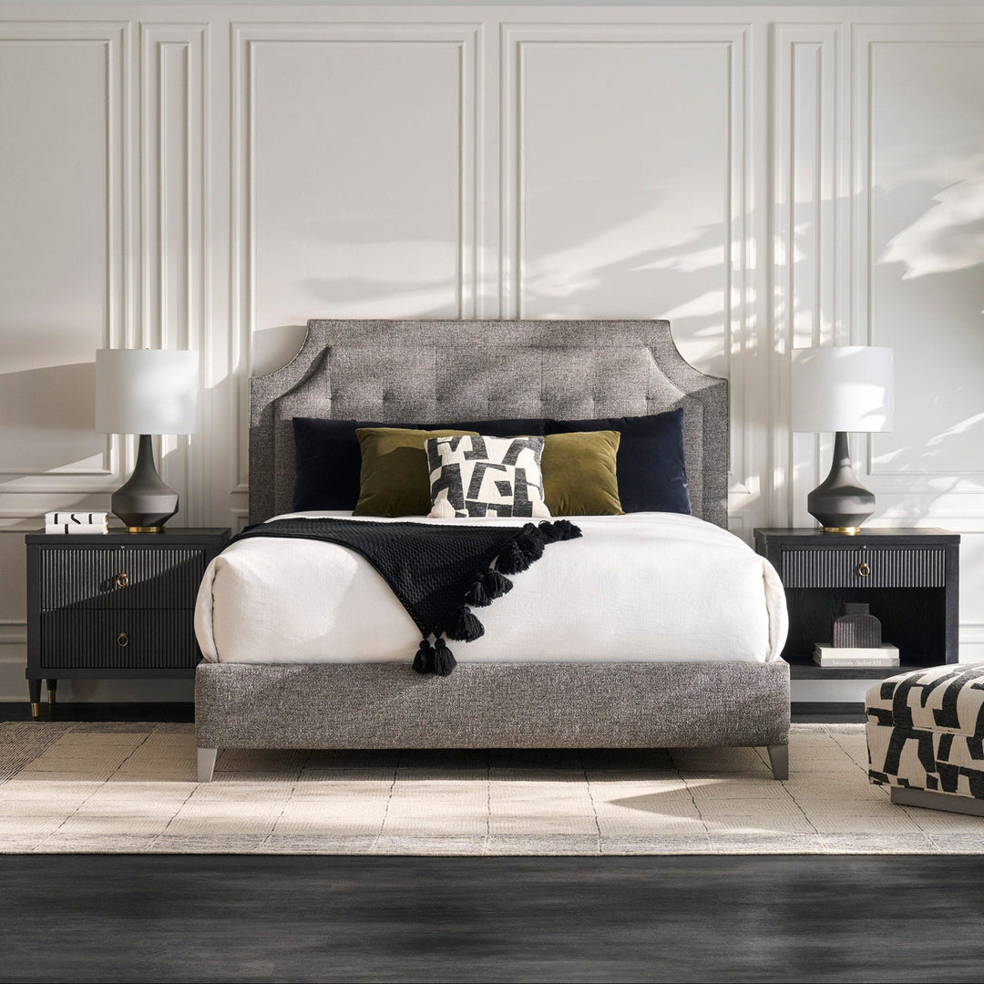 Modern bedroom with gray upholstered bed, nightstands, and decorative elements.