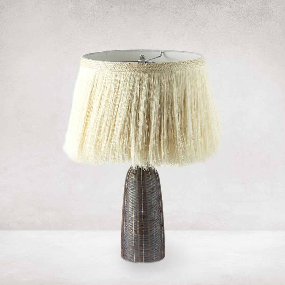 Front view of the Sisa Table Lamp in earthtone striped ceramic with ivory fringed shade