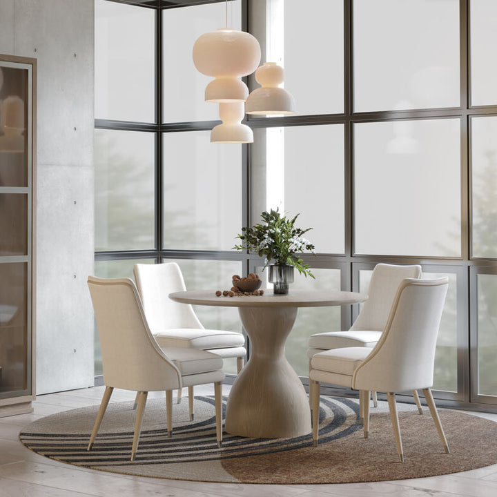 Modern dining room with a round table and chairs near a large window.